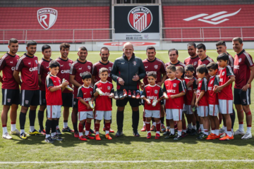 Jogadores do River Plate realizando doações de botines e sapatilhas para jovens atletas das divisões de base, destacando a camaradagem e solidariedade no clube.